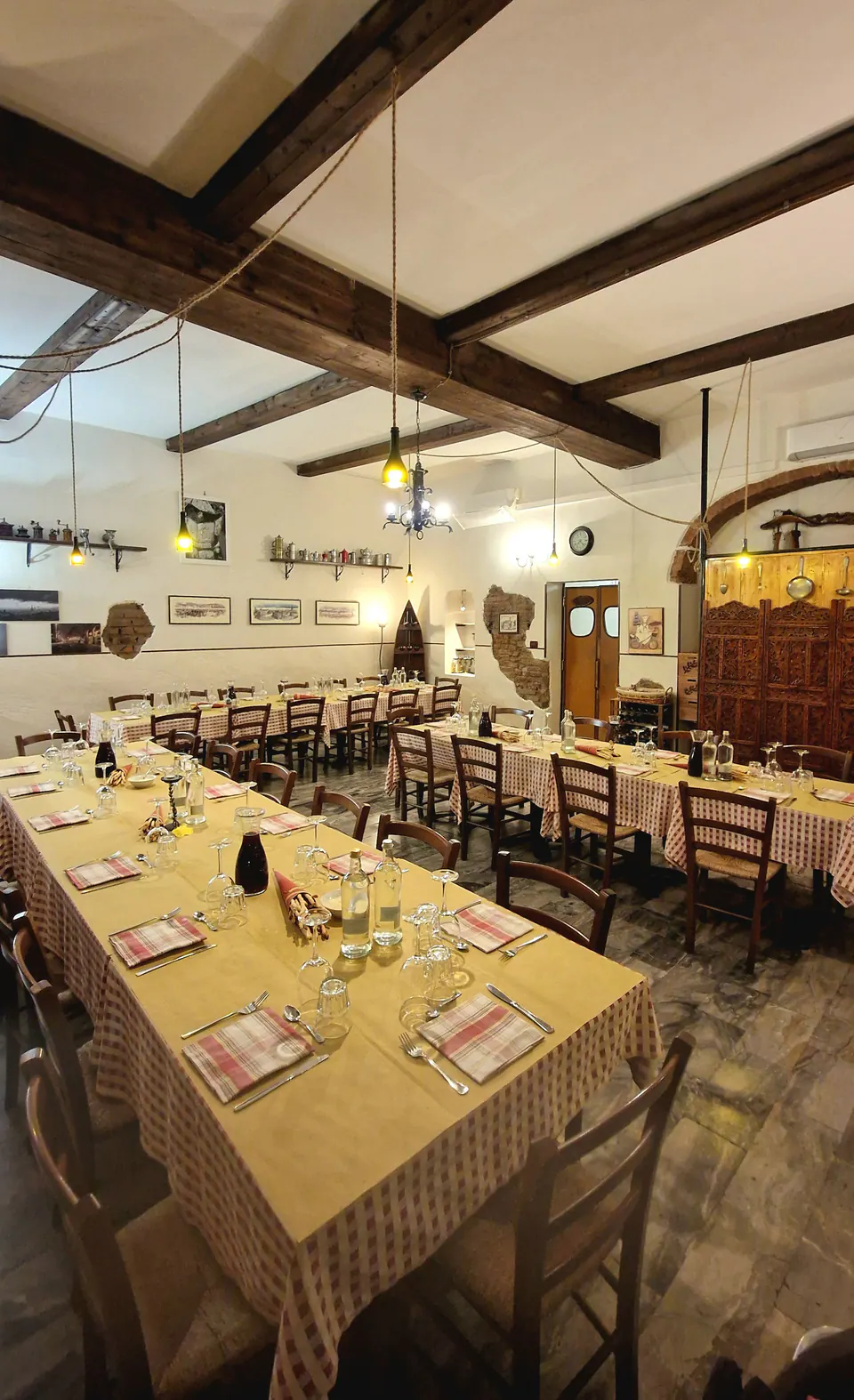 Una lunga tavolata apparecchiata per un gruppo sotto le travi in legno della sala grande